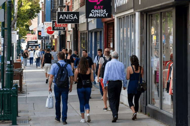 People walking past local businesses on an Alberta neighbourhood street